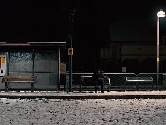 Ensam person sitter på parkbänk och chattar in till Röda Korsets Ungdomsförbunds stödchatt Jourhavande Kompis för att prata med en annan ung.